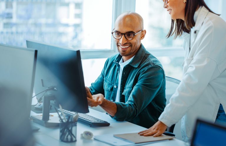 Software engineers using a computer and having a discussion in an office. Two creative business people working on a new coding project together.